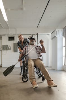 Man in wheelchair using VR headset for rehabilitation, assisted by friend.