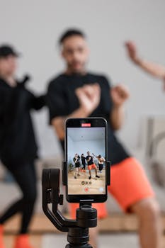 A group of people recording a dance video using a smartphone indoors.