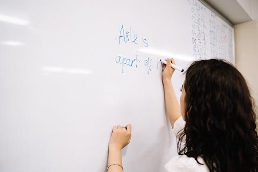 Woman writing on a whiteboard in office setting, focusing on teamwork and planning.